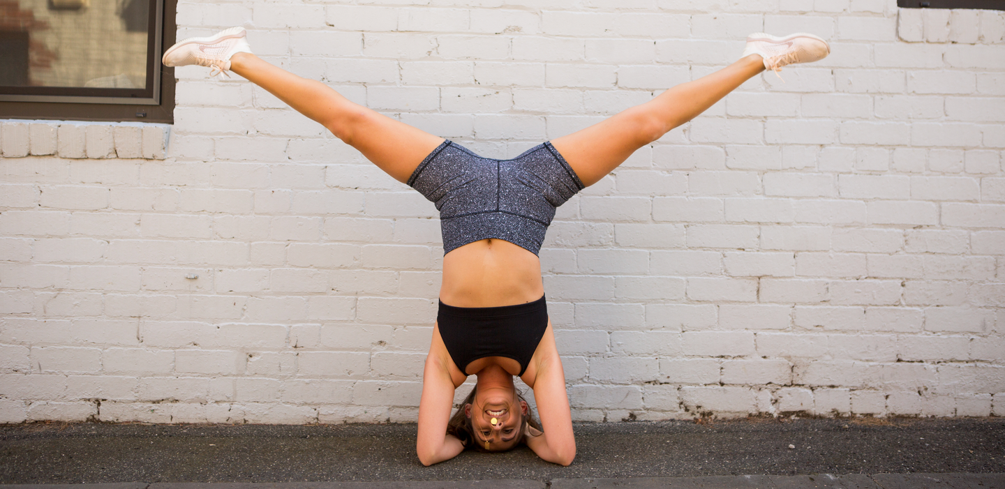 girl in headstand smiling with inner happiness